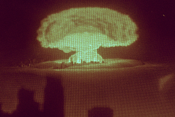 Kaukaa näkyy ydinpommiräjähdyksen sienipilvi.