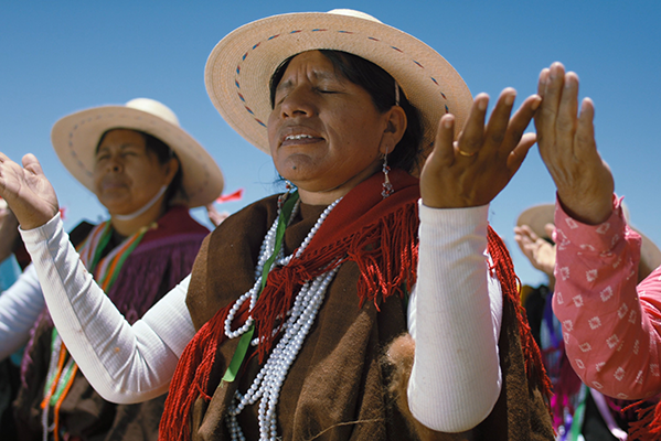 Andien alkuperäiskansalaisia seisoo yhdessä kämmenet taivasta kohti.