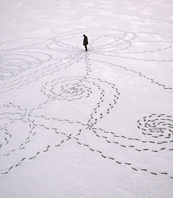 Hahmo seisoo keskellä lumeen tekemiänsä koukeroisia jalanjälkiä.