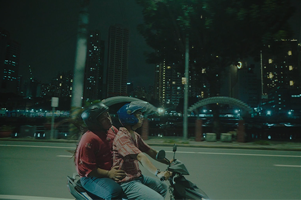 Two people riding a motorcycle at night.