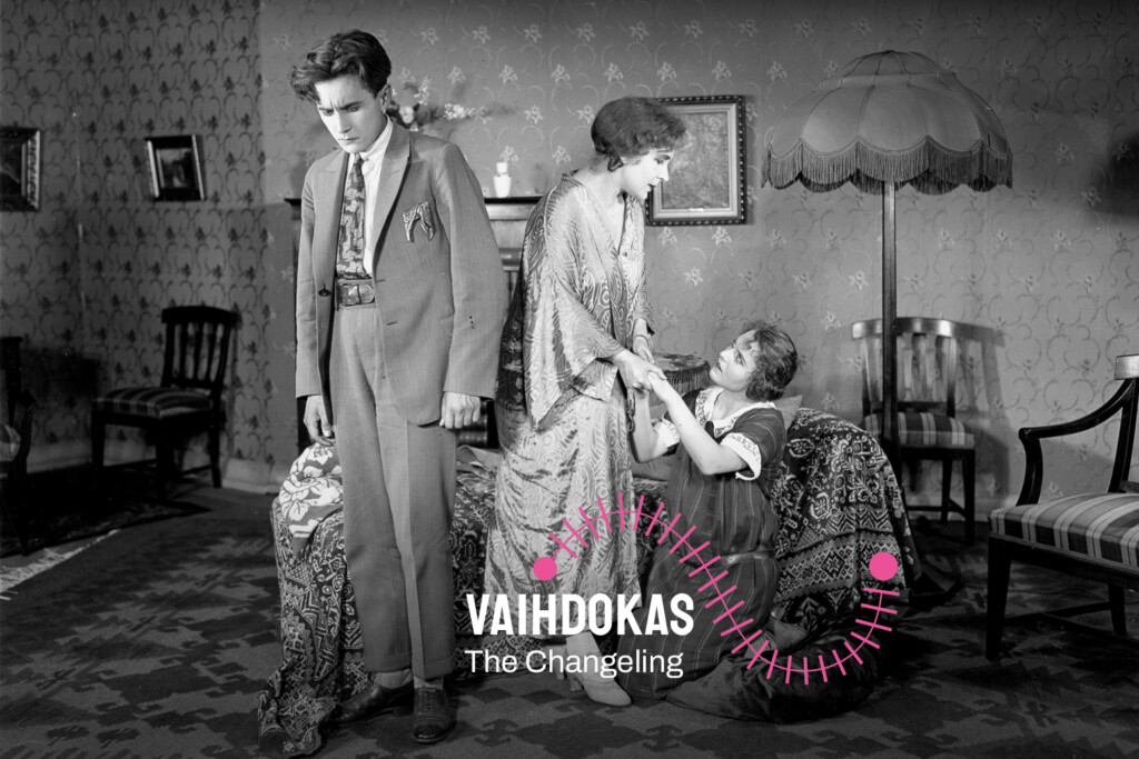 Vaihdokas / The Changeling. Mustavalkoisessa kuvassa vasemmalla seisoo mies, joka katsoo lattiaan. Vieressä oikealla kaksi naista, joista toinen istuu sohvalla ja toinen seisoo. Naiset pitävät toisiaan käsistä kiinni.