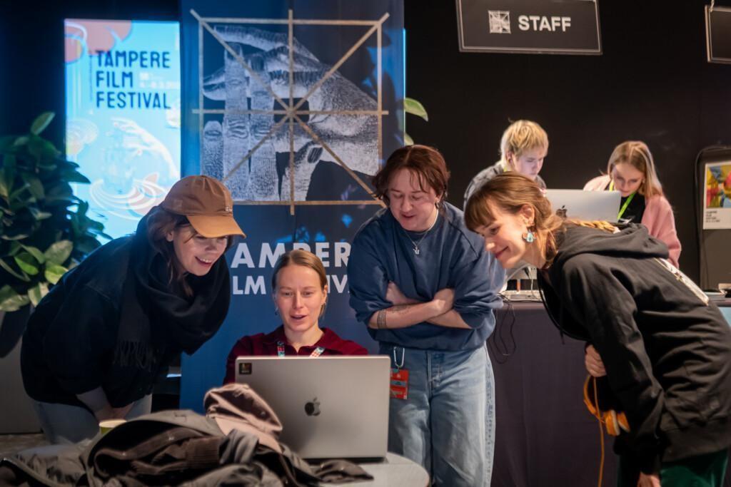 Festivaalin työntekijöitä katsomassa läppärin näyttöä.